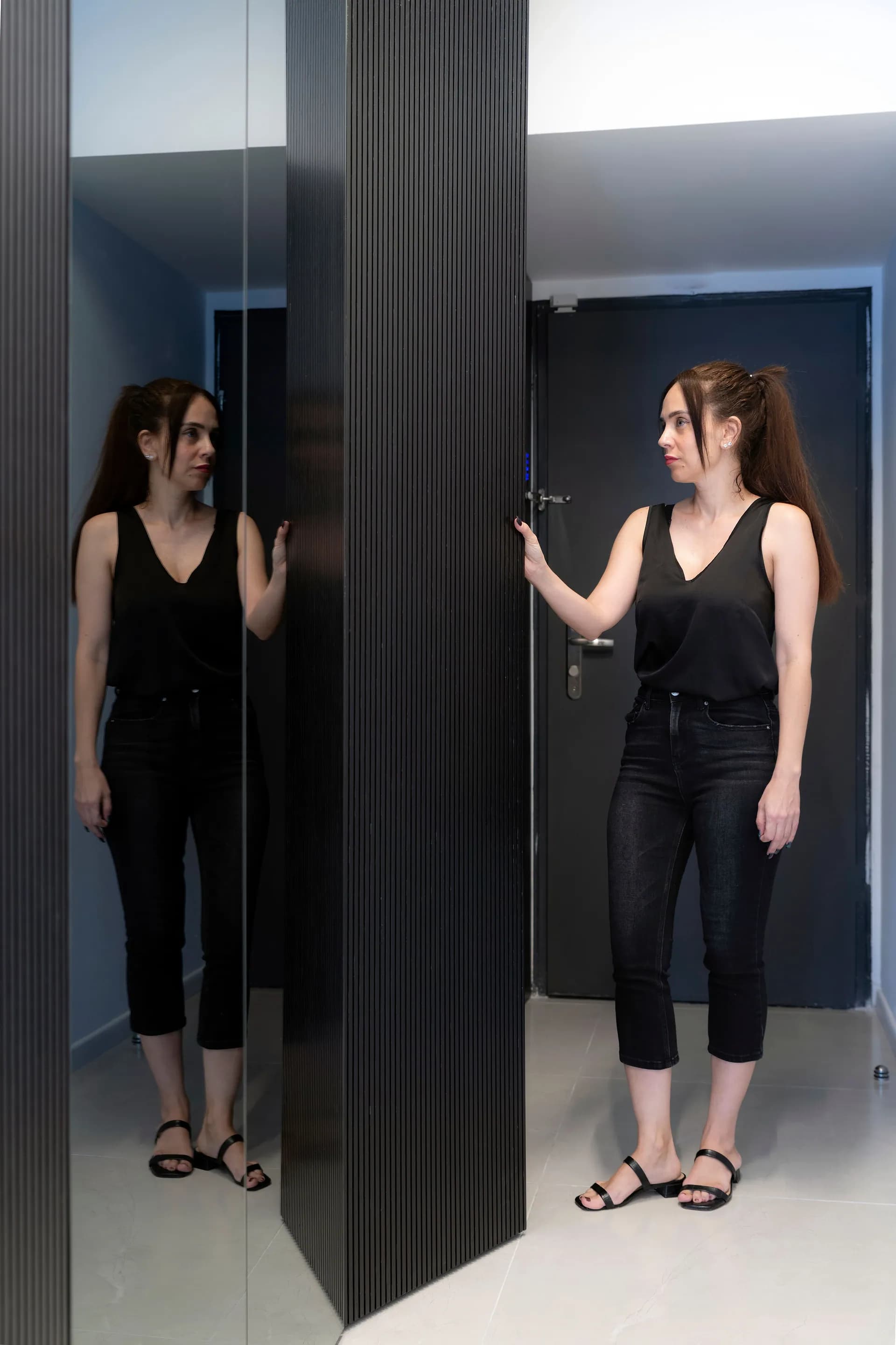 שתי נשים עומדות ליד ארון כהה גדול עם דלתות גבוהות