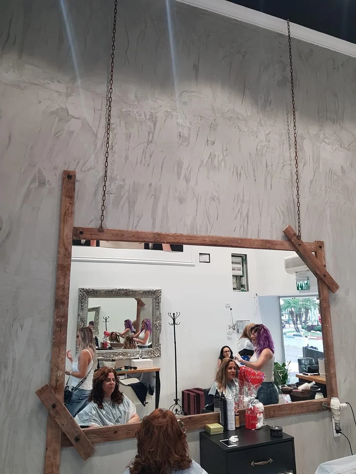 מראת מספרה גדולה במסגרת עץ עם אנשים המשתקפים במראה