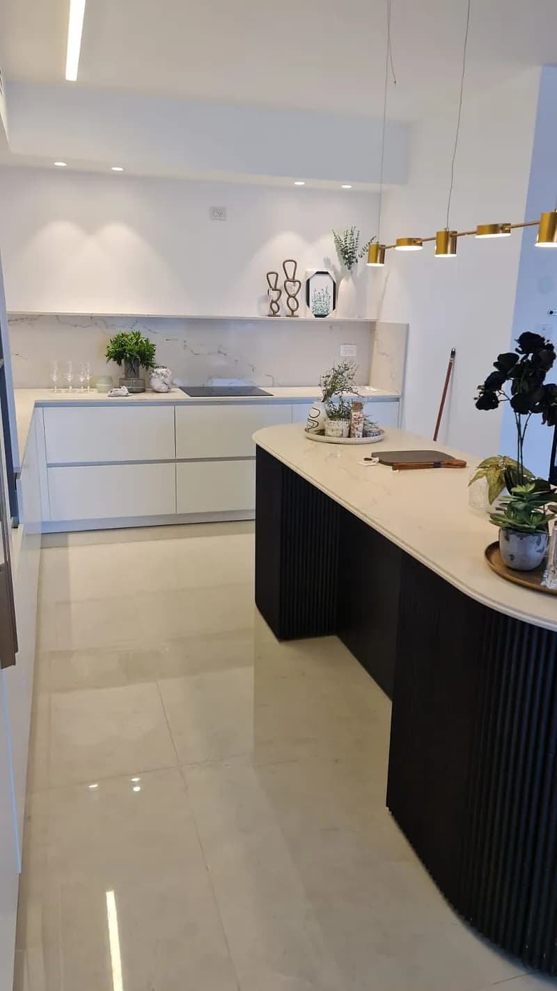 מטבח לבן מודרני עם אי שחור מעוגל וארונות תחתונים לבנים