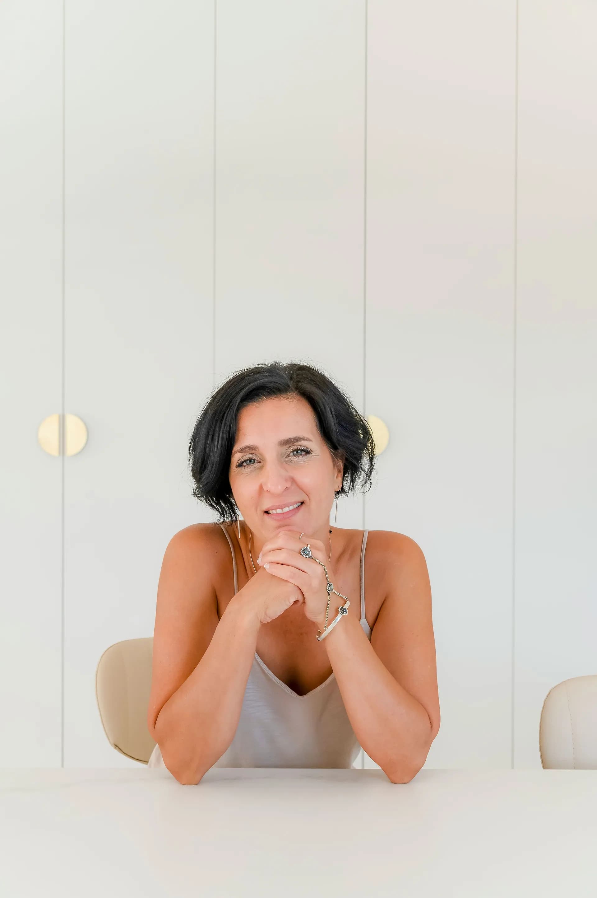 אדם יושב לפני ארון לבן גבוה עם ידיות זהב, בחלל מואר בגוונים בהירים.