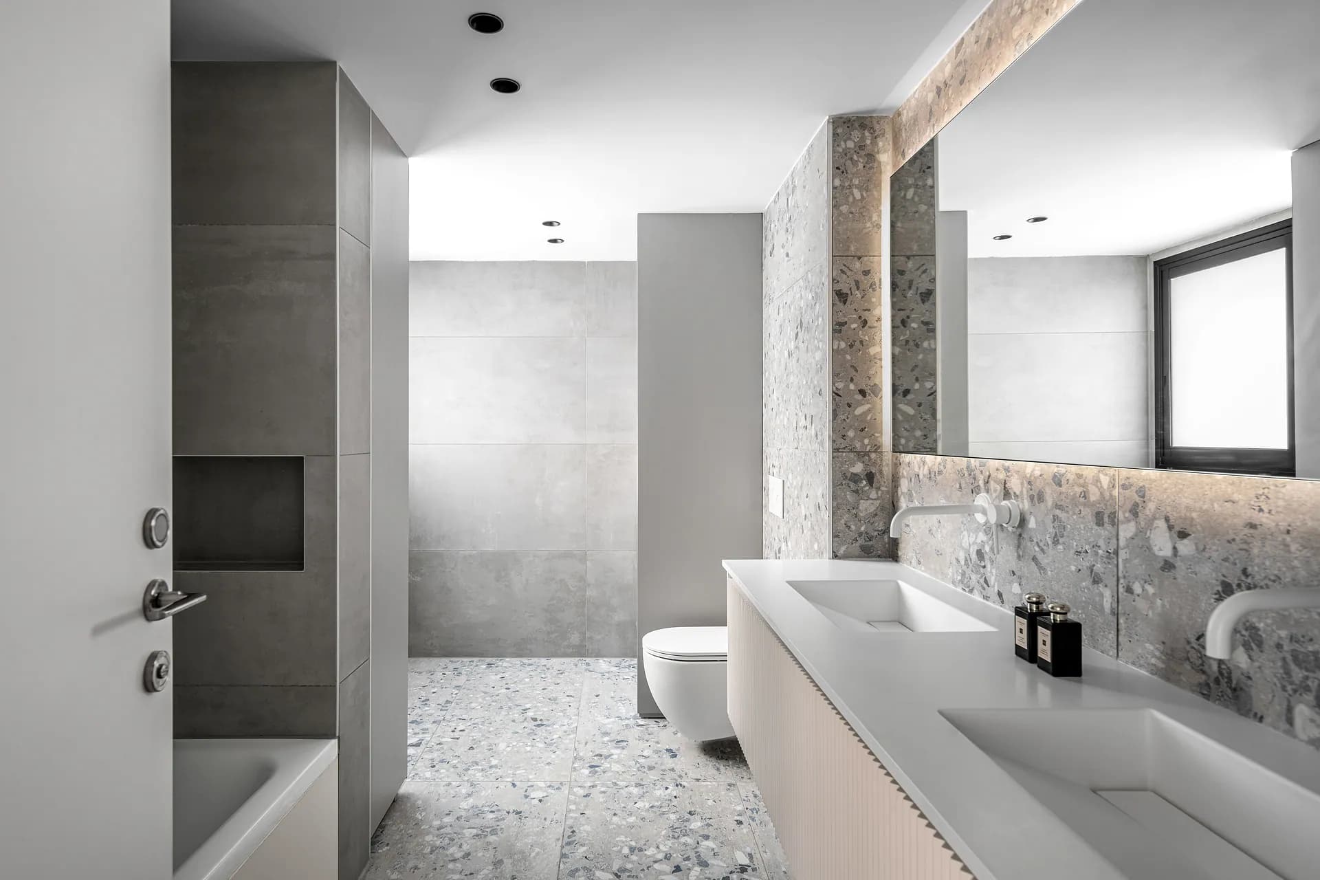 חדר רחצה בהיר עם מראה, ארון כיור וחיפוי קיר אפור