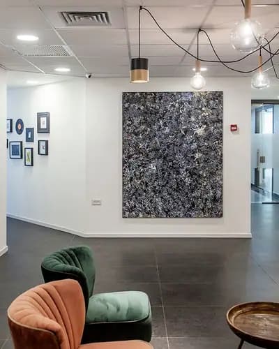 קיר מרכזי עם פסיפס דקורטיבי ולצידו כיסאות בחלל פנים